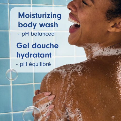 A person with a joyful expression in the shower, lathering their shoulder with white soap suds. Text reads "Moisturizing body wash - pH balanced" and "Gel douche hydratant - pH équilibré."