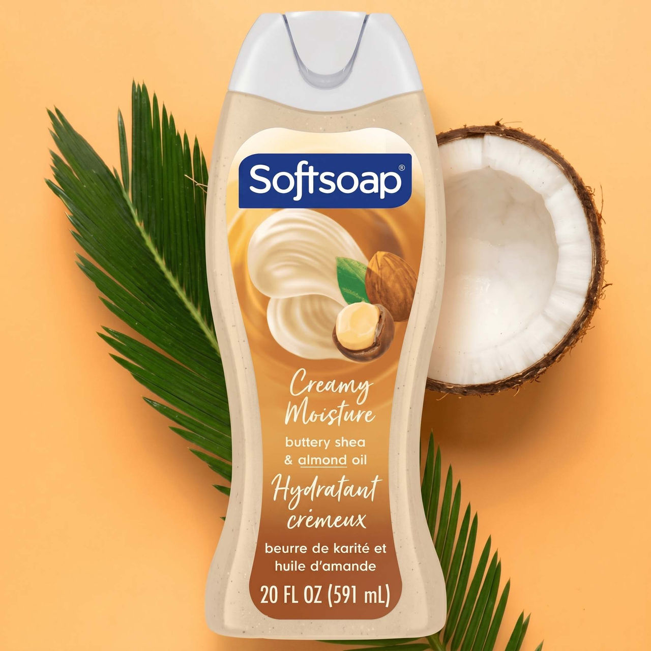 Nettoyant pour le corps Softsoap Hydratation crémeuse avec huile de karité et d'amande, étiquette en anglais et en français canadien, avec une noix de coco et une feuille de palmier sur fond orange.