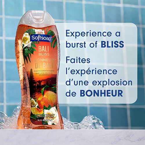 Flacon de savon Softsoap Bali Bliss posé sur un rebord en marbre, avec des bulles sur fond bleu. Inscription en anglais et en français : Vivez une explosion de pur bonheur.