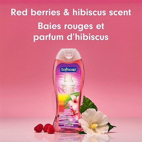 Le flacon de gel douche Fiji Nights repose sur une surface rose, à côté de framboises rouges fraîches et d'une fleur d'hibiscus blanche. Un grand texte situé au-dessus indique : « Red berries & hibiscus scent » et « Baies rouges et parfum d’hibiscus ».