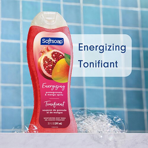 Flacon Softsoap « Grenade et Mangue Spritz » dans une douche aux carreaux bleus, entouré de bulles. Le texte, en anglais et en français, indique : « Moisturizing body wash » / « Gel douche hydratant ».