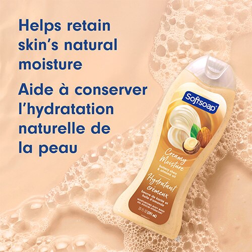 Flacon de savon Softsoap Buttery au beurre de karité et à l'huile d'amande sur un fond beige mousseux. Texte en anglais et en français : Aide à conserver l’hydratation naturelle de la peau.