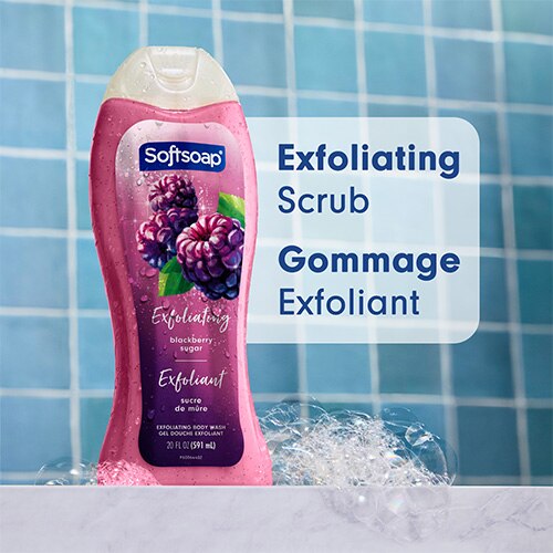 Une bouteille de gel douche Softsoap « Blackberry Sugar » posée sur une surface en marbre, entourée de bulles de savon. L'arrière-plan présente des carreaux de salle de bain bleus. Un texte en surimpression indique « Exfoliating Scrub » et « Gommage Exfoliant ».