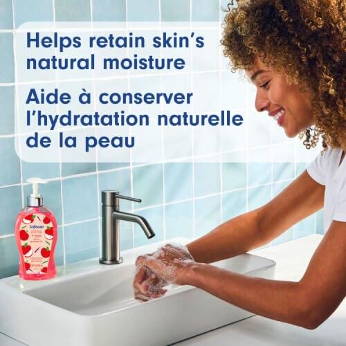 Une femme souriante se lavant les mains avec une mousse savonneuse au-dessus d'un lavabo. Le texte indique : « Aide à préserver l'hydratation naturelle de la peau », en anglais et en français.