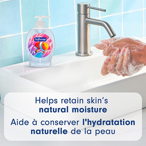 Bouteille Softsoap Aquarium sur un lavabo à côté du robinet, avec des mains qui moussent. Texte : « Aide à conserver l'hydratation naturelle de la peau ».