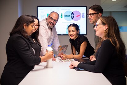 Équipe de professionnels en réunion de marketing autour d'une table avec écran affichant des diagrammes de produits de consommation.